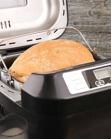 A black bread maker with a golden brown bread inside