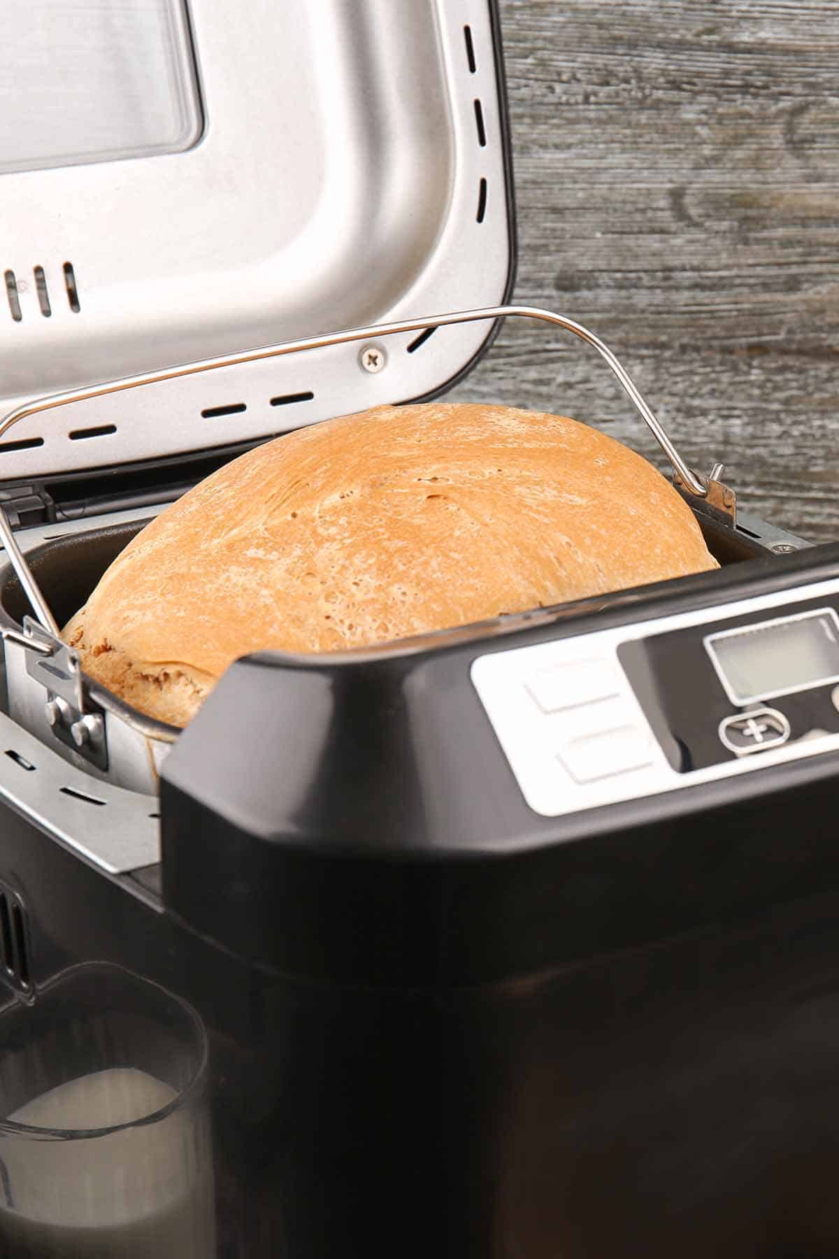 A black bread maker with a golden brown bread inside