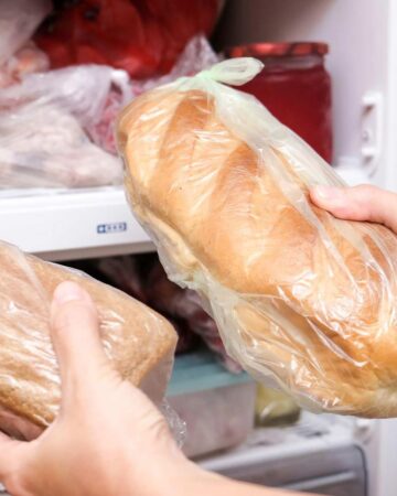Hands holding frozen bread in front of freezer